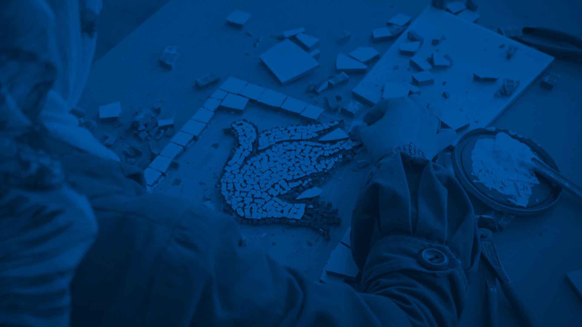 A woman makes a mosaic of a dove on a wooden table