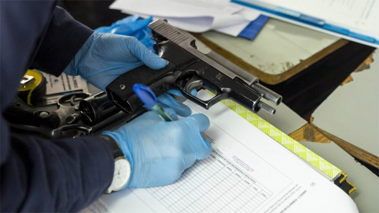 A police officer registers information about a handgun