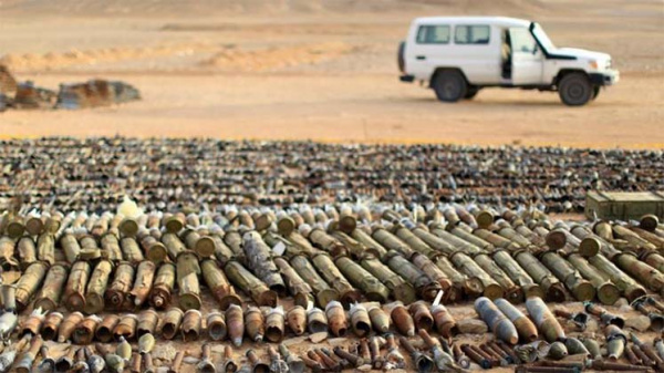 Arms and munitions laid out in the desert in front of a white UN truck