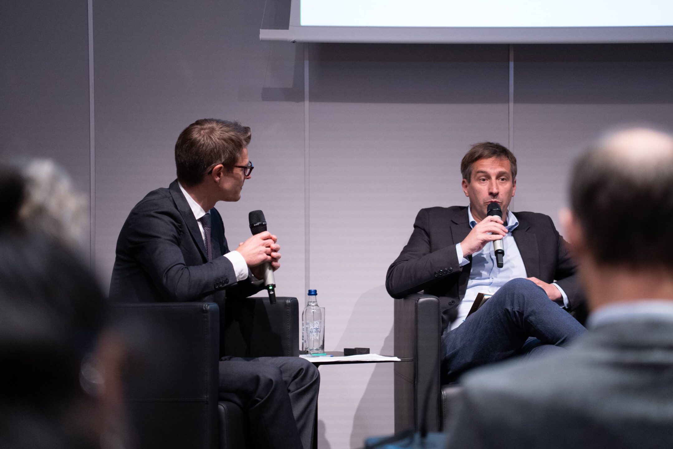 Two panellists in armchairs, one speaking into a microphone while the other listens, during a discussion at the launch of the Lomé Initiative’s third phase at the Geneva Peace Forum.