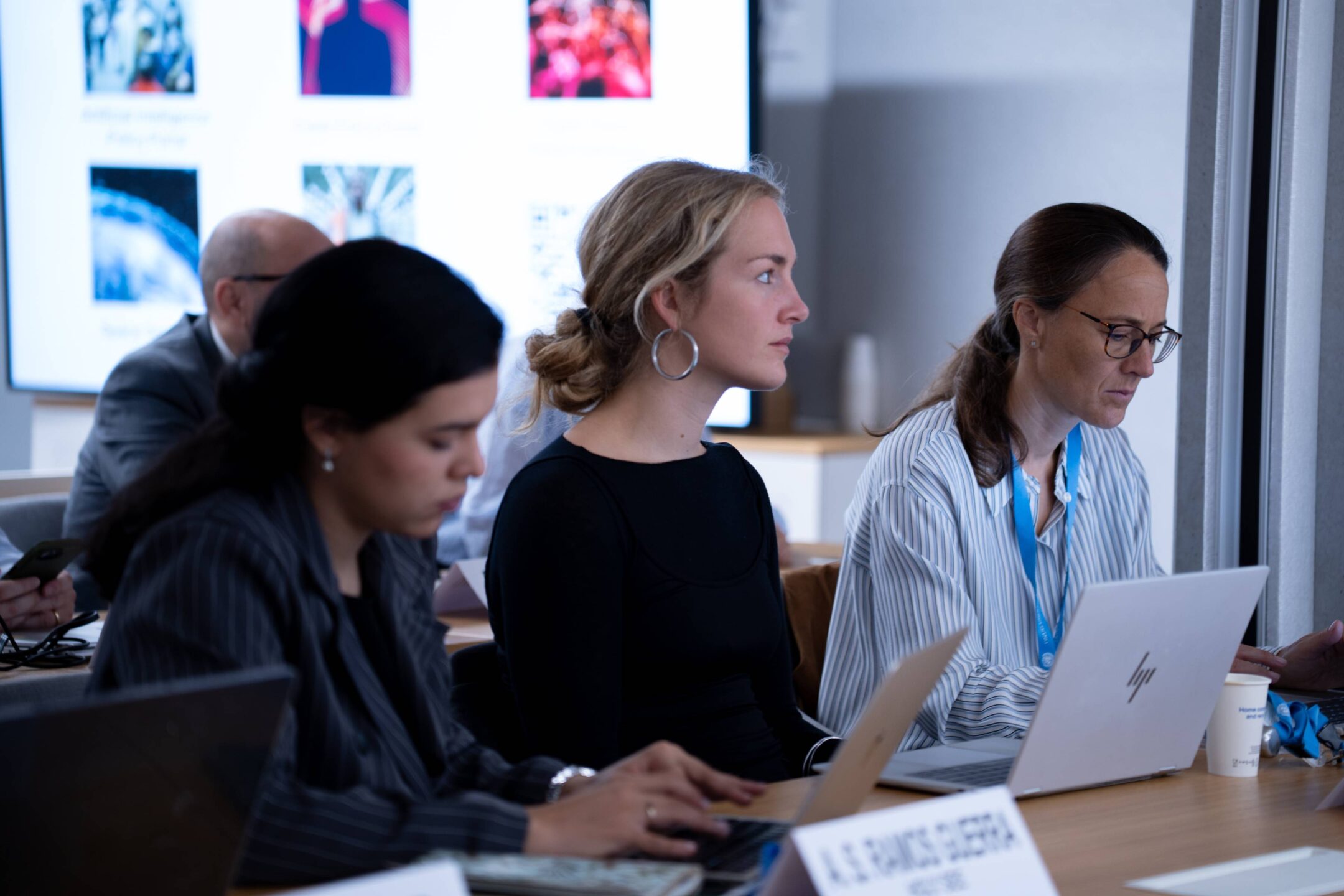 Delegates working on laptops and following a presentation during the 2026 Disarmament Orientation Course in Geneva, with a screen showing UNIDIR focus areas in the background.